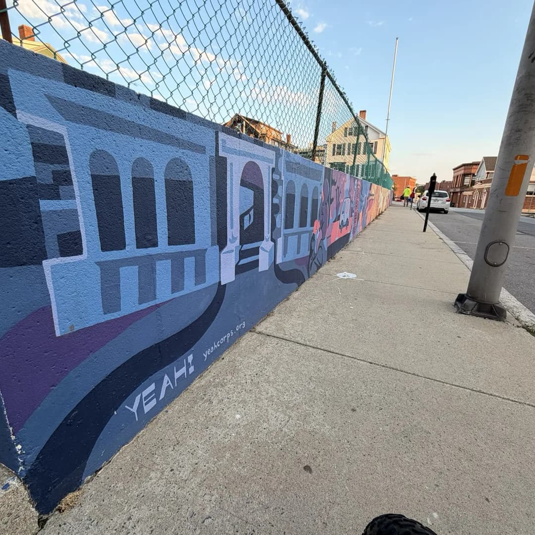 Community mural of Fall River landmarks painted along a sidewalk retaining wall