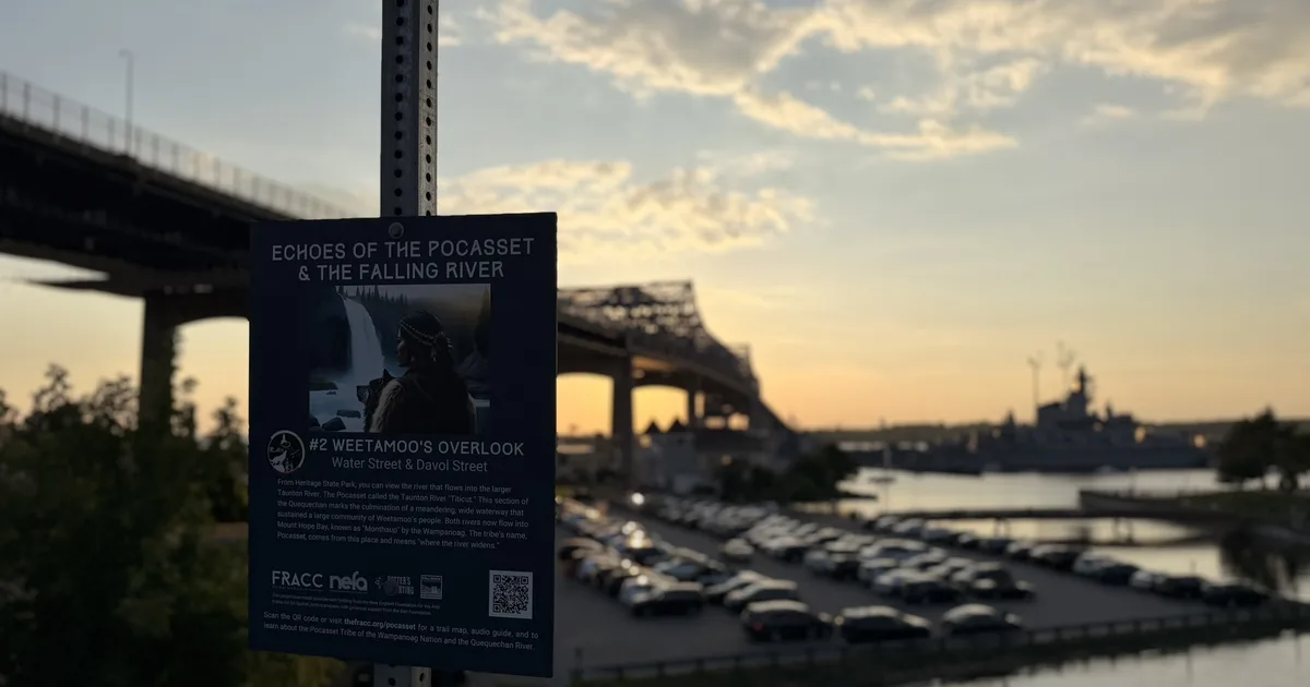Weetamoo's Overlook interpretive sign above Battleship Cove with the Braga Bridge and USS Massachusetts at dusk
