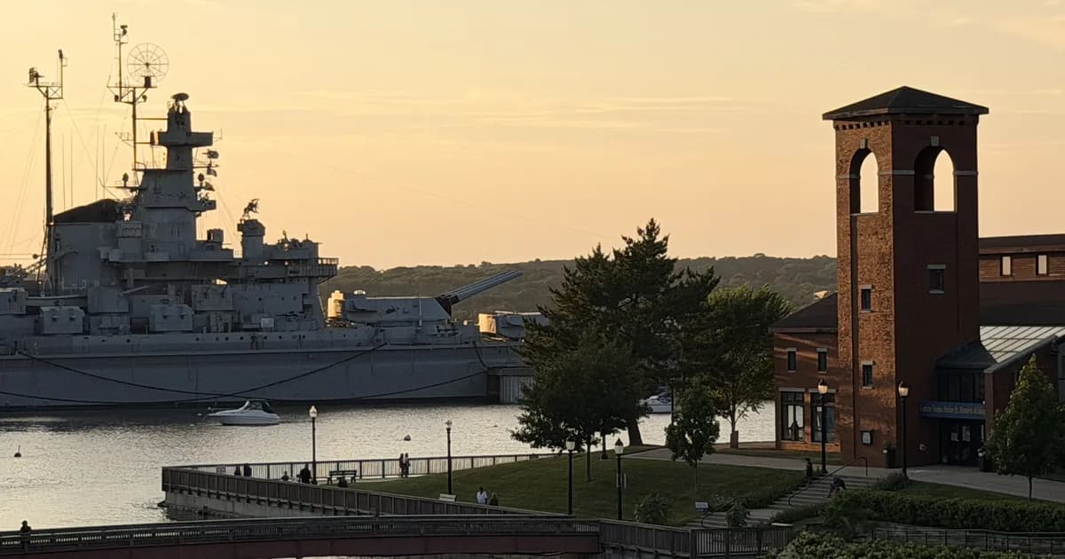 The battleship USS Massachusetts and the brick tower of the Fall River Maritime Museum at Battleship Cove at sunset