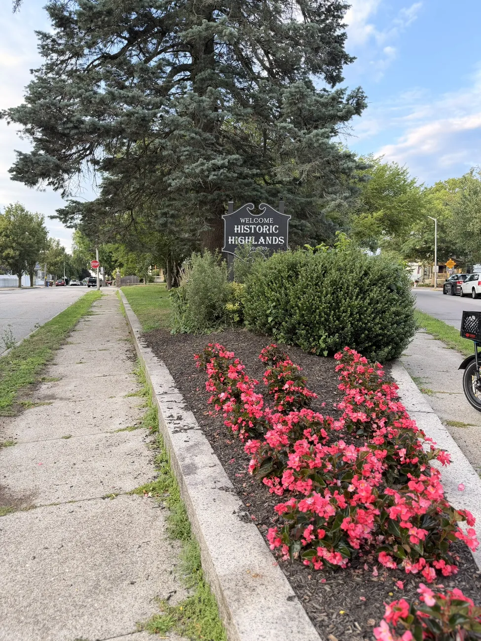 The Historic Highlands marker and a median planted with red begonias.