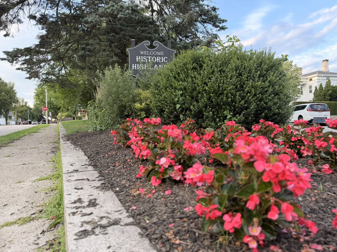 The Historic Highlands marker and a median planted with red begonias.