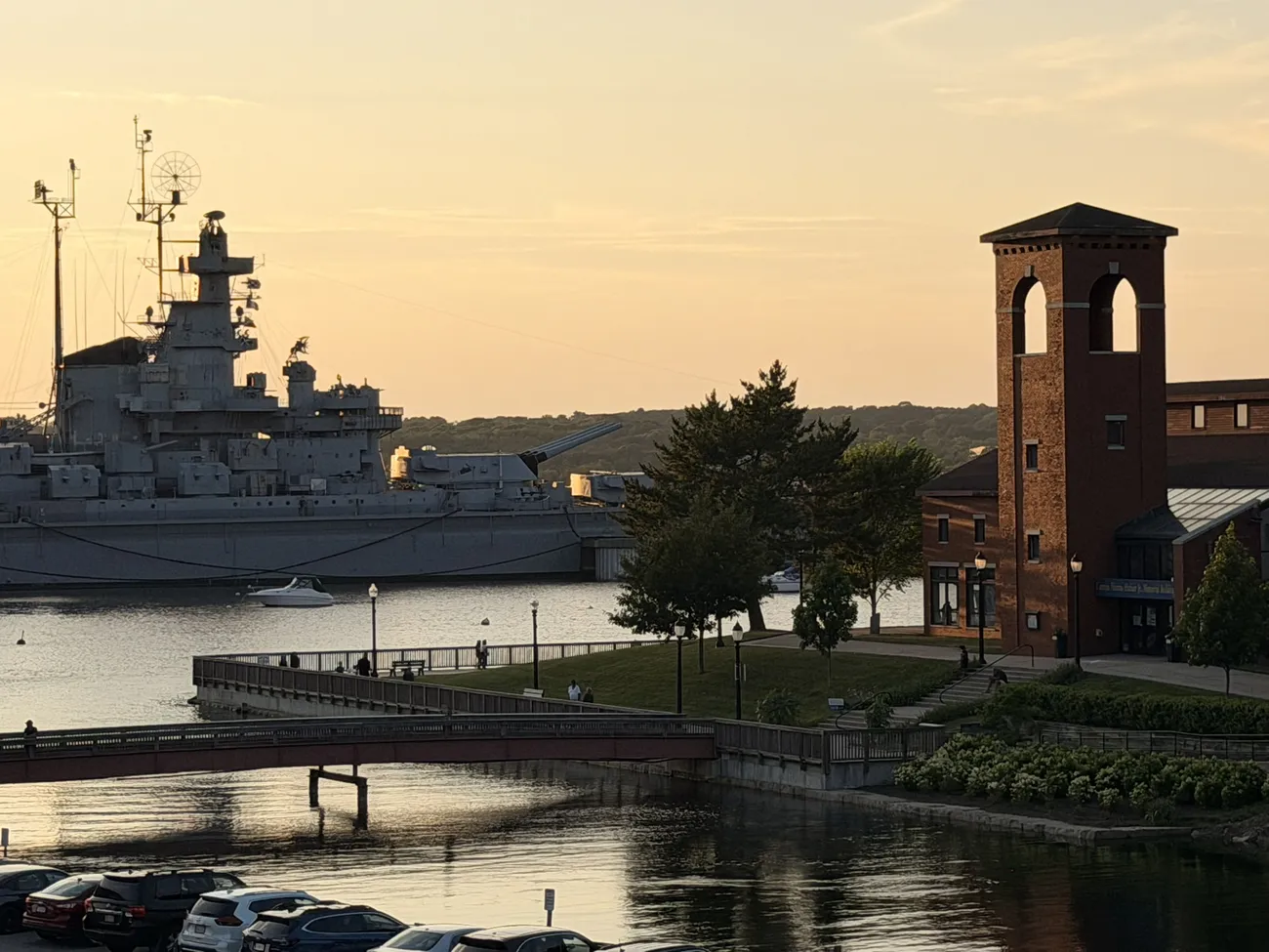 Battleship Cove at golden hour, the USS Massachusetts on still water.