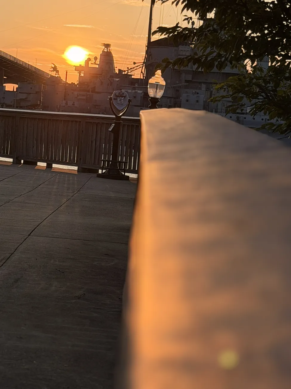 The waterfront boardwalk at golden hour, lamps coming on along the rail.