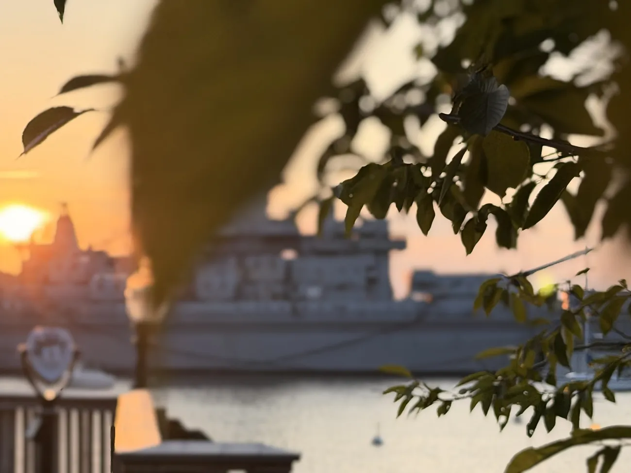 The waterfront boardwalk at golden hour, lamps coming on along the rail.